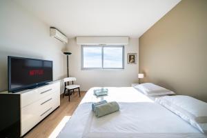 sypialnia z dużym białym łóżkiem i telewizorem z płaskim ekranem w obiekcie Baie Roquebrune, Balcon Vue Mer, Parking Gratuit - AO w mieście Roquebrune-Cap-Martin