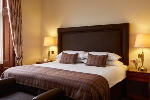 a hotel room with a large bed with pillows at The Grange Manor in Grangemouth
