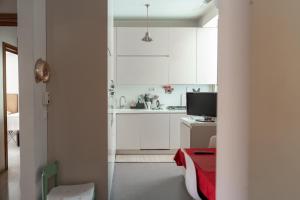 una piccola cucina con armadi bianchi e tavolo rosso di Casa dei Ruscelli a Bari