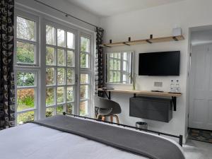 a bedroom with a bed and a desk with a tv at Spring Cottage B&B in Probus