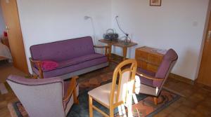 una sala de estar con un sofá púrpura y sillas en Appartement dans un chalet avec jardin en Nax