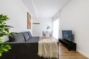 ein Wohnzimmer mit einem Sofa und einem Flachbild-TV in der Unterkunft Acojedor y exclusivo loft by Lofties in Terrassa