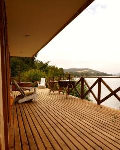 a wooden deck with a table and chairs on the water at Cabañas Nativo D'Ko in Carahuo