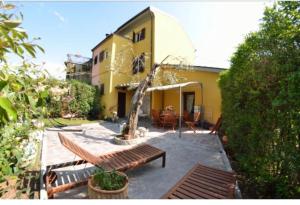 a patio with benches in front of a yellow house at Casamalu in Lucca