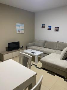 sala de estar con sofá y TV en Jasmine Apartments, en Sarandë