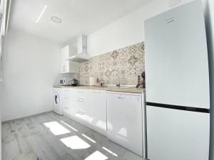 a kitchen with white appliances and a refrigerator at Buhardilla en calle Ancha, pleno centro in Sanlúcar de Barrameda