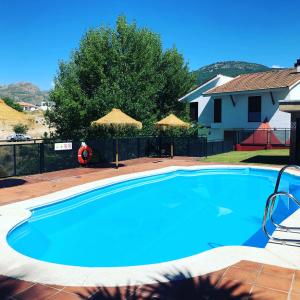ein großer blauer Pool mit Sonnenschirmen im Hof in der Unterkunft La Casa del Pianista in Monachil