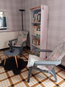 a room with two chairs and a book shelf at Les Hortensias 26 in Saint-Laurent-sur-Mer