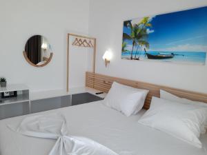 Un dormitorio con una cama blanca y una foto de la playa en Anxhelos Hotel, en Himare