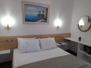 a bedroom with a white bed and a mirror at Anxhelos Hotel in Himare