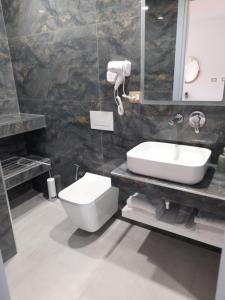 a bathroom with a sink and a toilet and a mirror at Anxhelos Hotel in Himare