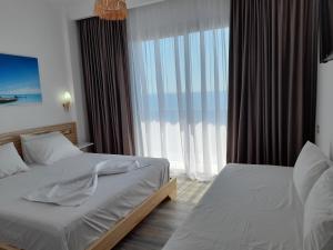 a bedroom with two beds and a large window at Anxhelos Hotel in Himare