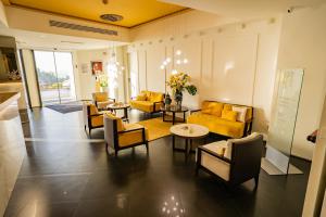 a living room with yellow couches and tables and chairs at Taormina Panoramic Hotel in Taormina