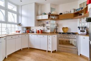 Biała kuchnia z drewnianą podłogą i białymi szafkami w obiekcie Appartement de charme en centre-ville pour 6 pers. w mieście Nantes