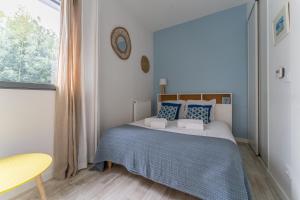 um quarto com uma cama com almofadas azuis e uma janela em Côté Port - Appt sortie privée vers le port em Arcachon