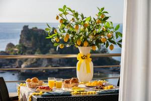 a table with breakfast foods and a vase of oranges at Taormina Panoramic Hotel in Taormina