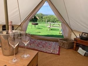 two wine glasses sitting on a table in a tent at Home Farm Radnage Glamping Bell Tent 6, with Log Burner and Fire Pit in High Wycombe