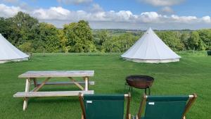 una mesa de picnic y dos tiendas en un campo en Home Farm Radnage Glamping Bell Tent 6, with Log Burner and Fire Pit, en High Wycombe