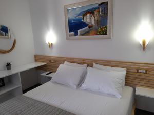 a bedroom with a white bed with a painting on the wall at Anxhelos Hotel in Himare