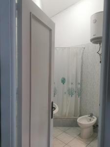 y baño con aseo y cortina de ducha. en Casa Giusi en Sferracavallo