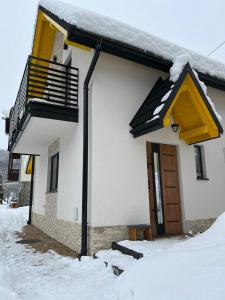 una casa blanca con nieve en el techo en Domek RogatY, en Szczawnica