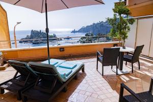 a patio with a table and chairs and an umbrella at Taormina Panoramic Hotel in Taormina