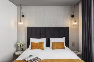 1 dormitorio con 1 cama grande con almohadas amarillas en Hôtel & Spa Le Maury, Vannes, The Originals Boutique en Vannes