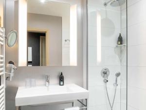 ピュトーにあるアパートホテル アダージョ ラ デファンス エスプラナードの白いバスルーム(シンク、シャワー付)