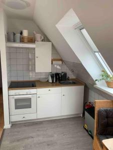 a kitchen with white cabinets and a sink in a attic at Über den Dächern der Stadt in Bremervörde