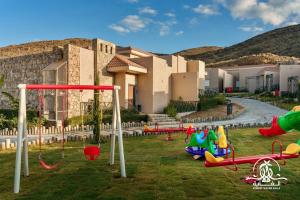 a group of playground equipment in front of a building at Shalalat Al Ghaba Chalets in Taif