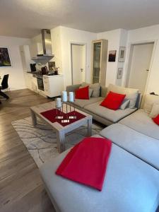 una sala de estar con 2 sofás blancos y almohadas rojas en Ferienwohnung mit Vollaustattung, en Waldbronn