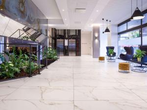 an office lobby with white marble floors and plants at Mercure Biel in Biel