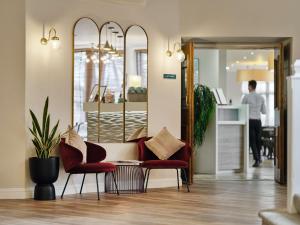 een woonkamer met 2 stoelen en een spiegel bij Linton Lodge a BW Signature Collection Hotel in Oxford