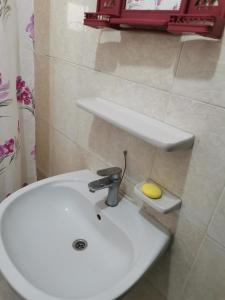 La salle de bains est pourvue d'un lavabo blanc et d'une éponge jaune. dans l'établissement شقه مفروشة الجبيهه, à Amman