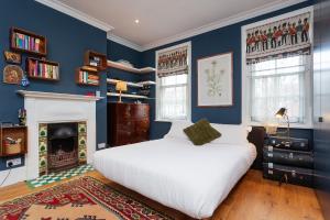 a blue bedroom with a bed and a fireplace at Veeve - Sunshine Botanical in London