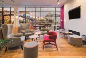a waiting room with chairs and tables and a tv at Vienna House Easy by Wyndham Pilsen in Plzeň
