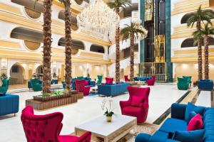 a lobby with palm trees and chairs and a chandelier at Ramada Plaza by Wyndham Silivri in Silivri