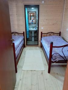 two beds in a room with a sink and a mirror at HOTEL AMIRAN in Tusheti