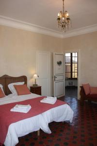 1 dormitorio con 2 camas y lámpara de araña en La Montagute, en Thézan-des-Corbières