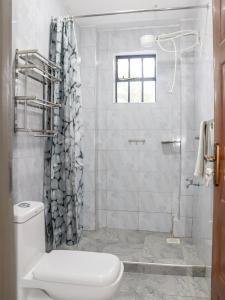 a white bathroom with a shower and a toilet at Weber Generations Accommodation in Naivasha