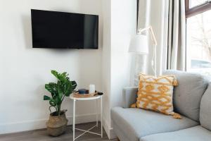 a living room with a couch and a tv on a wall at Stylish 2 Bedroom Flat in Ilford, London in Ilford