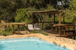 a swimming pool with a gazebo and a table and chairs at Baluleni Safari Lodge in Grietjie Game Reserve