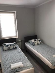 twee bedden in een kleine kamer met een raam bij LOQUS Apartamenty Studia Pokoje in Płock