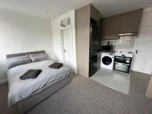 a bedroom with a large bed and a washing machine at Spectacular Modern, Brand-New, 1 Bed Flat, 15 Mins Away From Central London in Hendon