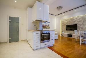 eine Küche mit weißen Schränken und ein Wohnzimmer in der Unterkunft Boutique Soho Apartment in Budapest