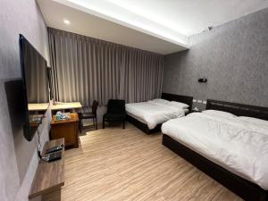 a hotel room with two beds and a flat screen tv at Five Rabbits in Chaozhou
