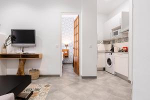 sala de estar blanca con TV y cocina en Edificio Conde 7- Plaza de la Merced, en Málaga