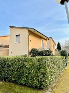 a house behind a hedge in front of a house at Appartamento Eldorado in Marina di Bibbona