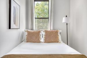 a white bedroom with a bed with pillows and a window at Park Slope 2BR w WD nr Barclays Center NYC-908 in Brooklyn