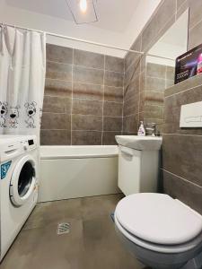 y baño con aseo y lavadora. en Family apartment near Palas Mall en Iaşi